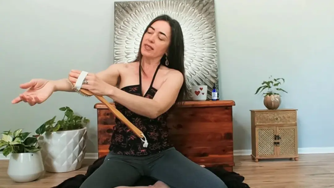 Dayana drawing a sacred oil brush along her forearm